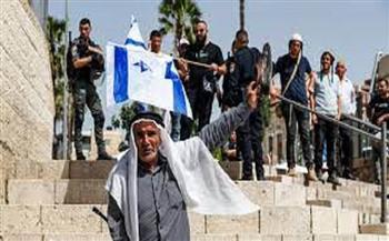 مستوطن يرفع علم إسرائيل خلال اقتحامه الاقصى