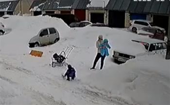 الأمومة تدفع سيدة لإنقاذ طفليها من كومة ثلجية ضخمة سقطت فجأة (فيديو)