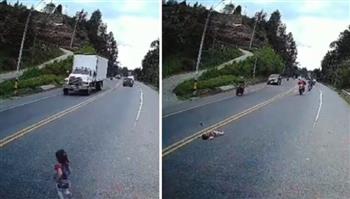 دراجة نارية تصدم طفلة وتحميها من الدهس تحت عجلات شاحنة (فيديو)