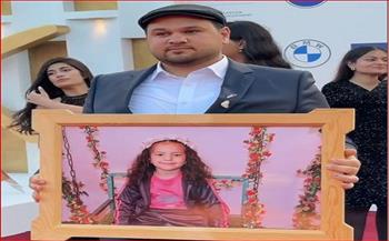 المخرج أمير ظاظا وفريق العمل يرفعون صورة الطفلة هند على السجادة الحمراء في الجونة