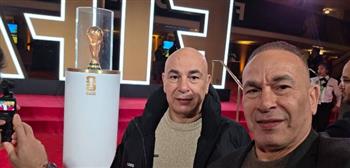 حسام وإبراهيم حسن يلتقطان صورة تذكارية مع كأس العالم قبل القرعة