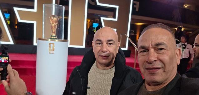 حسام وإبراهيم حسن يلتقطان صورة تذكارية مع كأس العالم قبل القرعة