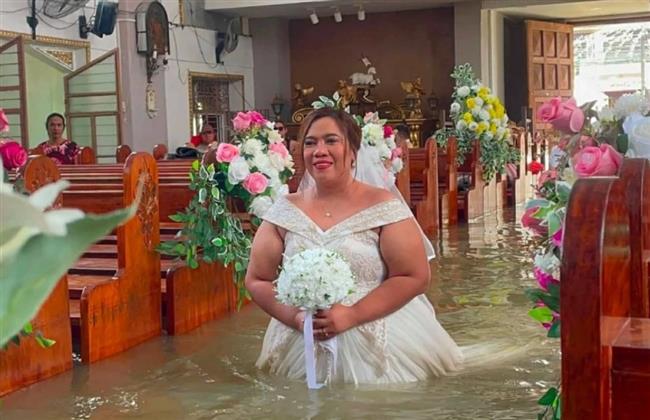 تريند العالم.. عروس بفستان الزفاف تمشي وسط مياه فيضانات الفلبين